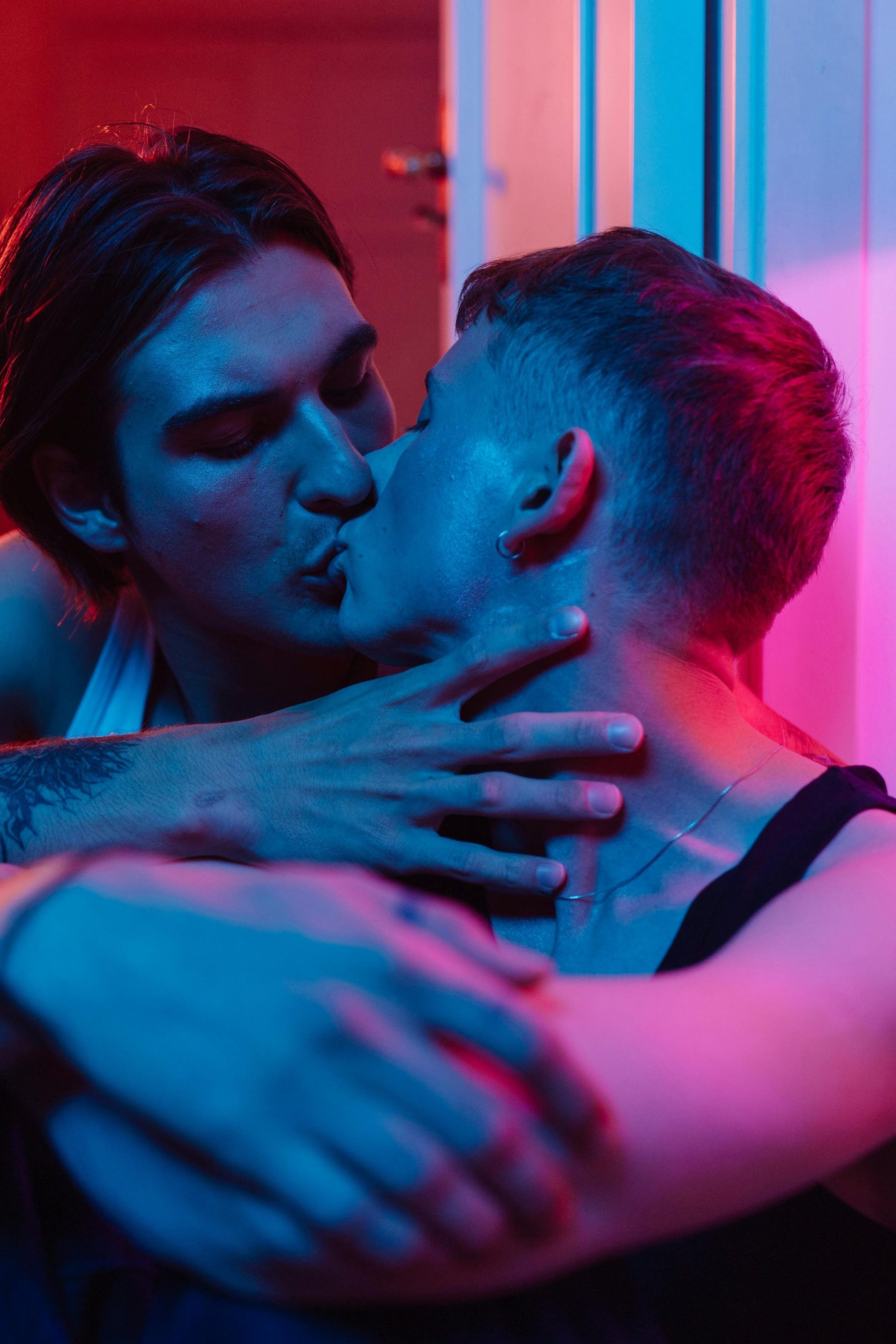Two men in intimate moment with neon blue and pink lighting